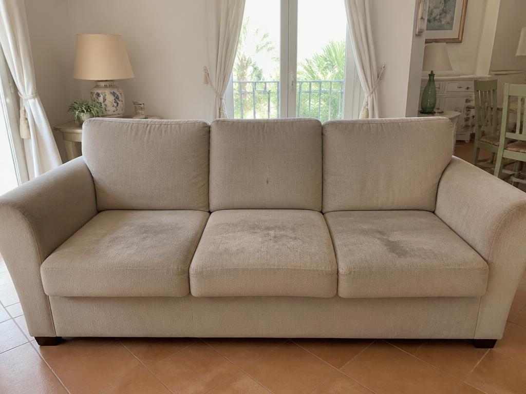 Sofá de tela beige con manchas y desgaste antes de la limpieza profesional en Palma de Mallorca