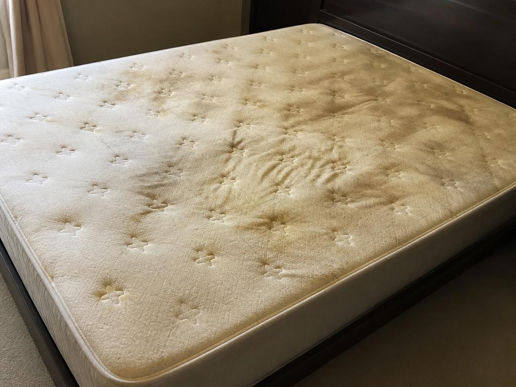 Colchón de matrimonio con manchas amarillas antes de la limpieza a domicilio en Mallorca